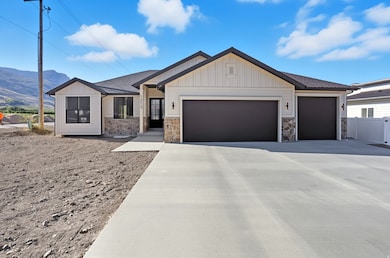 View of front of house with stone siding, roof with shingles, and board and batten siding