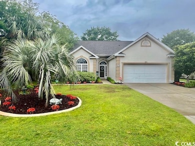 View of front facade featuring an attached garage, concrete driveway, a front yard, and stucco siding