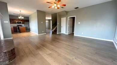 Unfurnished living room with visible vents, stairway, ceiling fan with notable chandelier, and light wood finished floors