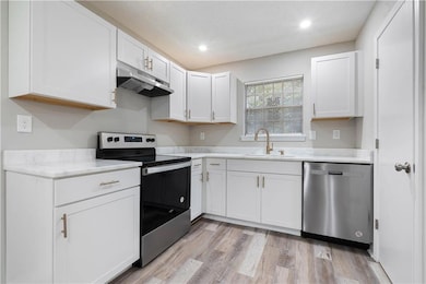 Kitchen with light hardwood / wood-style flooring, sink, stainless steel appliances, and white cabinetry