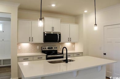 Kitchen with stainless steel appliances, white cabinets, a kitchen island with sink, tasteful backsplash, and ornamental molding