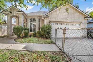 View of front of home featuring brick siding, an attached garage, roof with shingles, and a gate