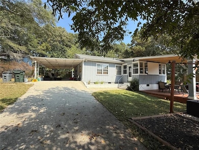 View of front of home featuring crawl space, concrete driveway, a wooden deck, a carport, and a front lawn