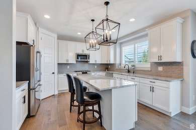 With chic lighting, crisp cabinetry with crown molding, granite countertops, and a spacious island for gathering.