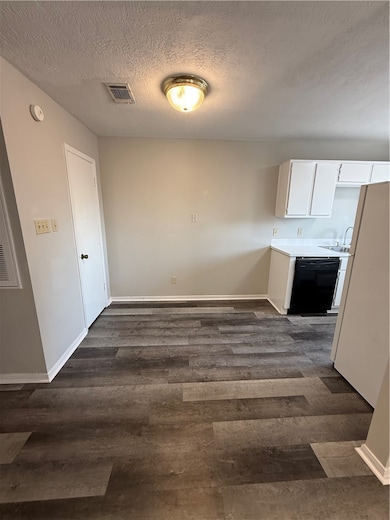 Unfurnished dining area featuring a textured ceiling and dark wood-style flooring