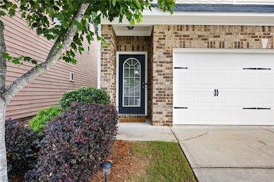Entrance to property with concrete driveway, brick siding, and an attached garage