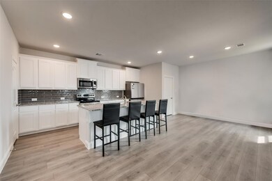 Kitchen featuring a kitchen island with sink, ligh