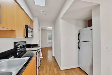 Kitchen featuring appliances with stainless steel finishes, light wood finished floors, light brown cabinets, and modern cabinets