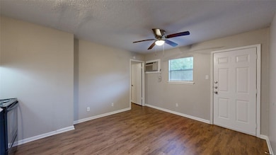 Entrance foyer featuring dark wood finished floors, a textured ceiling, ceiling fan, and an AC wall unit