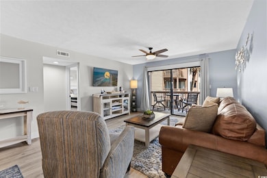 Living room featuring wood finished floors, a ceiling fan, and a textured ceiling
