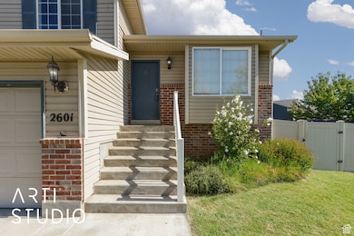 View of exterior entry with brick siding, a garage, and a gate