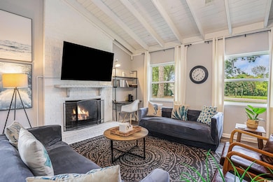 Living room featuring a fireplace, high vaulted ceiling, a wooden ceiling with exposed beams, and wood finished floors