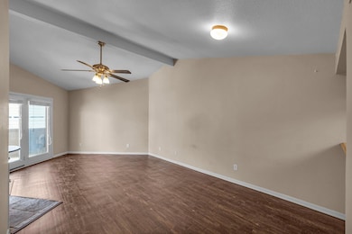 Empty room with lofted ceiling with beams, dark wo
