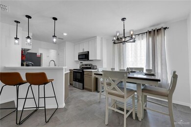 Kitchen with stainless steel electric stove, a chandelier, a breakfast bar, a peninsula, and light countertops
