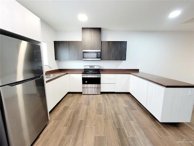 Kitchen featuring stainless steel appliances, a sink, modern cabinets, dark countertops, and recessed lighting