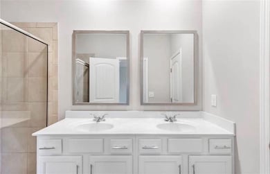 Full bath featuring a stall shower and double vanity