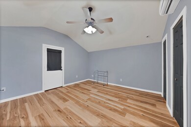 Bonus room featuring lofted ceiling, light wood-style floors, a wall unit AC, and ceiling fan