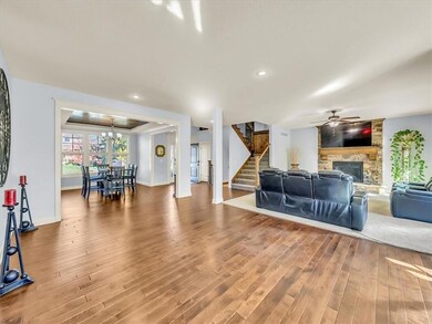 Living room featuring a fireplace, ceiling fan with notable chandelier, and hardwood / wood-style flooring