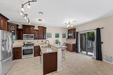 Kitchen featuring tasteful backsplash, glass insert cabinets, stainless steel appliances, a breakfast bar area, and a peninsula