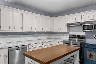 Kitchen featuring white cabinetry, butcher block c