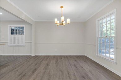 Empty room with a chandelier, wood finished floors, crown molding, and a wainscoted wall