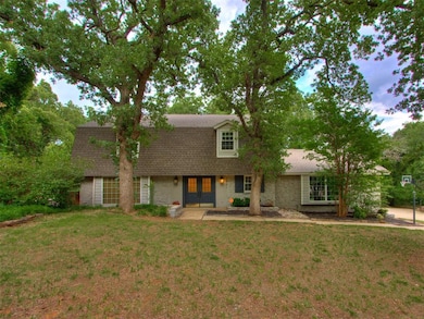 Colonial inspired home with roof with shingles, french doors, stone siding, and a front lawn