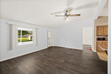Unfurnished living room with vaulted ceiling, dark wood-style floors, and ceiling fan
