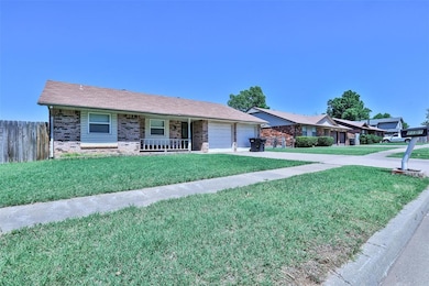 Single story home with brick siding, covered porch, a garage, and driveway