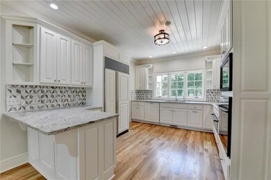 Kitchen featuring open shelves, a peninsula, paneled appliances, white cabinets, and recessed lighting