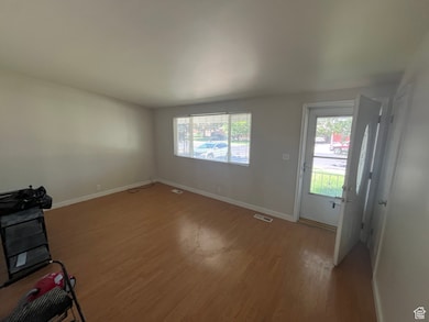 Unfurnished living room with light wood-style floors and baseboards