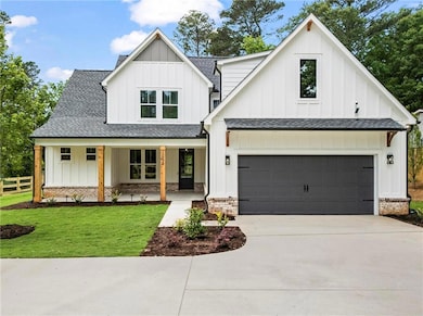 Modern inspired farmhouse with board and batten siding, a shingled roof, and driveway