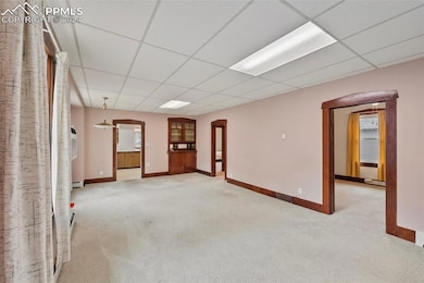 Carpeted empty room featuring a drop ceiling