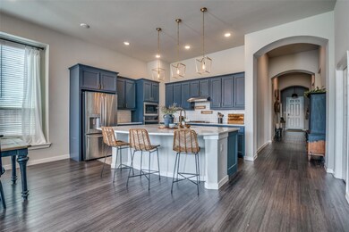 Kitchen featuring a vast island with sink, designer hanging light fixtures, stainless steel appliances, finishes, and tasteful backsplash