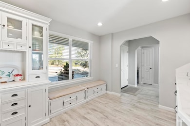 Mudroom with light wood finished floors, arched walkways, and recessed lighting
