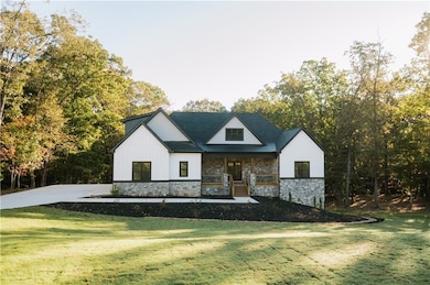 Modern inspired farmhouse with covered porch, a metal roof, a front yard, and stone siding