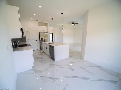 Kitchen featuring decorative light fixtures, light stone counters, recessed lighting, white cabinetry, and an island with sink