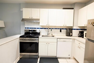 Kitchen featuring appliances with stainless steel finishes, tasteful backsplash, light countertops, and white cabinets