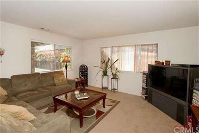 The living room has carpeting, a brick wood burnin