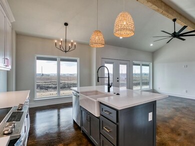 Kitchen with pendant lighting, lofted ceiling with beams, white cabinets, a center island with sink