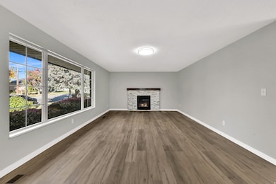 Unfurnished living room with a stone fireplace and dark wood-style flooring