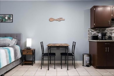 Kitchen featuring backsplash, dark brown cabinetry, and light tile patterned floors