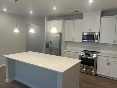 Kitchen with stainless steel appliances, tasteful backsplash, white cabinetry, a center island, and recessed lighting