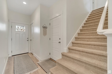 Foyer with light wood-style floors, recessed lighting, and stairs