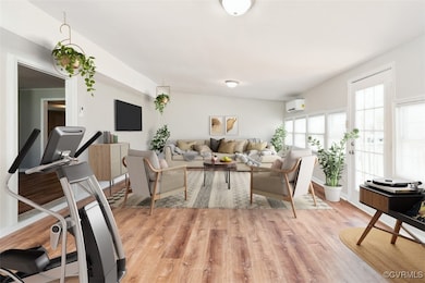 Living area with an AC wall unit and light wood-st