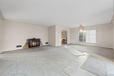 Unfurnished living room with carpet, a fireplace with flush hearth, and arched walkways