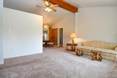 Carpeted living room with beamed ceiling, high vaulted ceiling, a ceiling fan, a baseboard radiator, and a chandelier