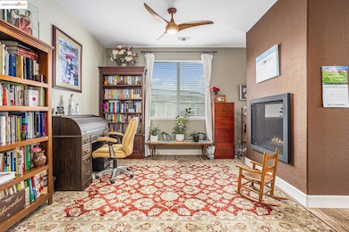 Office with a textured wall, a ceiling fan, and light wood-type flooring