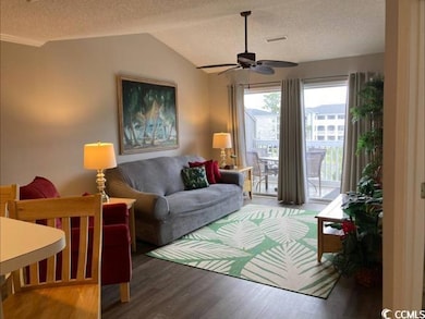 Living area with a textured ceiling, wood finished floors, a ceiling fan, and vaulted ceiling
