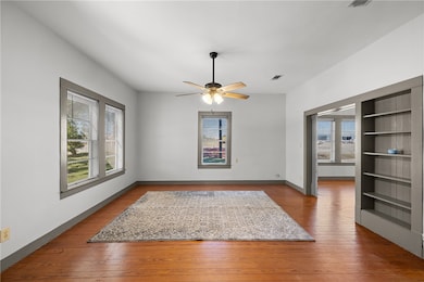 Spare room with hardwood / wood-style floors, ceiling fan, and built in shelves