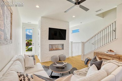 Living room featuring a stone fireplace, ceiling f